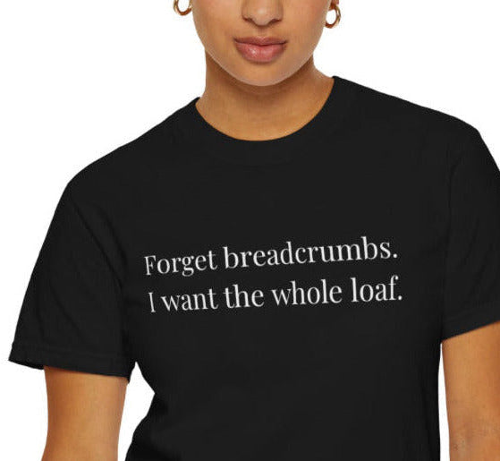 Woman wearing a black t-shirt with text Forget breadcrumbs. I want the whole loaf. in a clean white editorial font on a white background