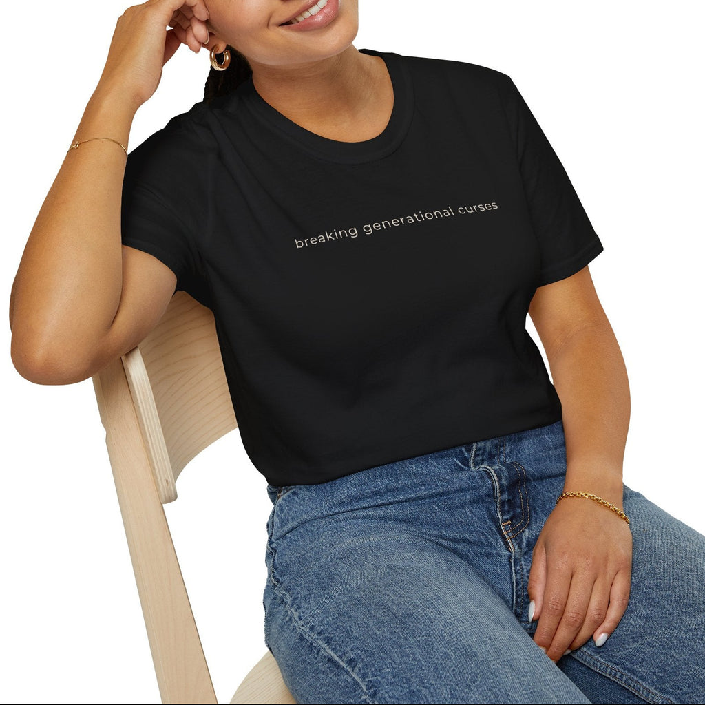 Woman wearing a black t-shirt with text, breaking generational curses sitting on a chair against a white background