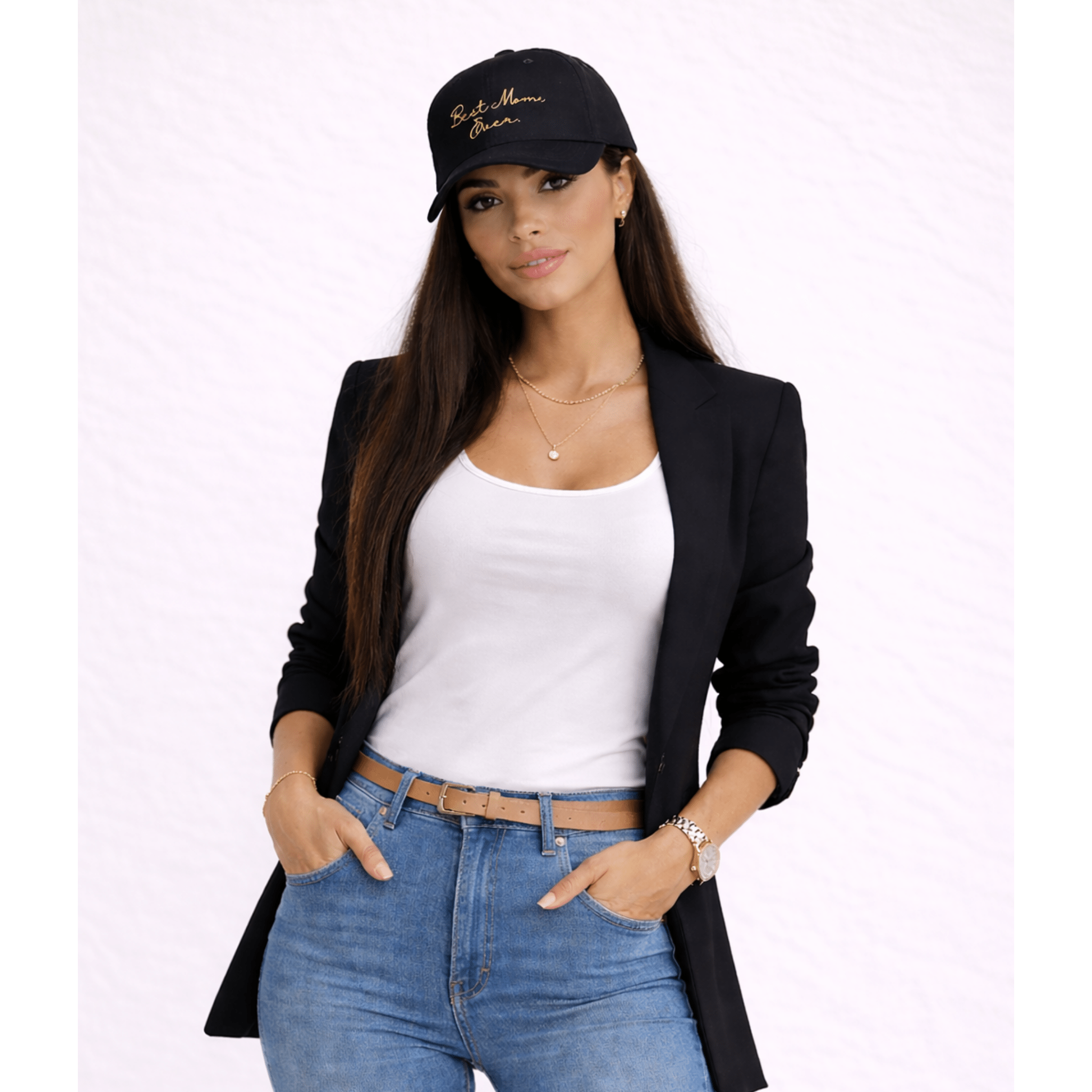 Woman wearing a black blazer, white top, blue jeans, and a black cap with gold text 'Best Mom, Ever.' on a white background