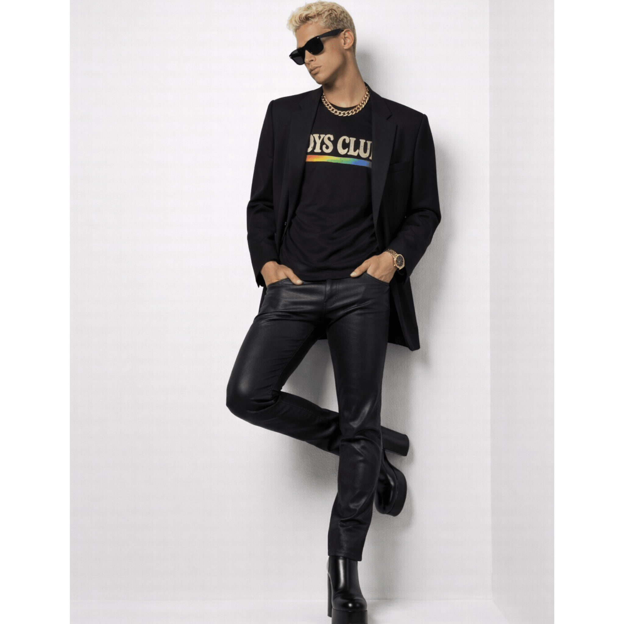 Male model wearing a black suit with a colorful shirt while posing against a white background