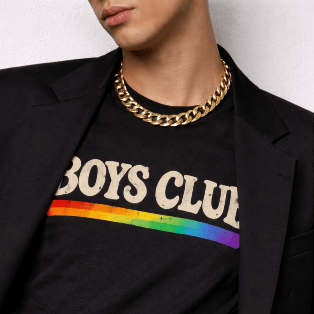 Person wearing a black 'Boys Club' t-shirt with rainbow stripe and gold chain necklace.