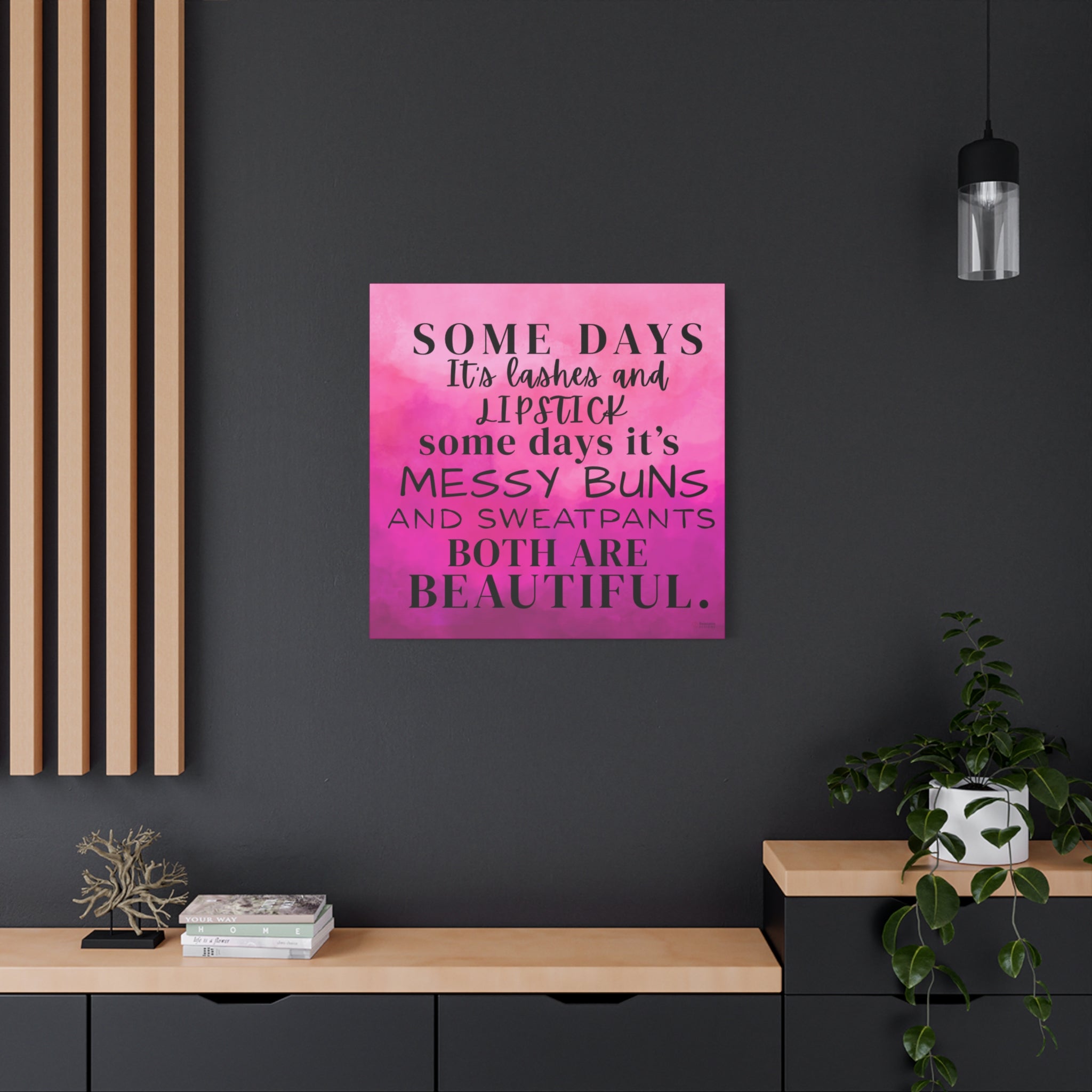 Decorative pink wall art with an inspirational quote on a dark wall with a modern interior setting.
