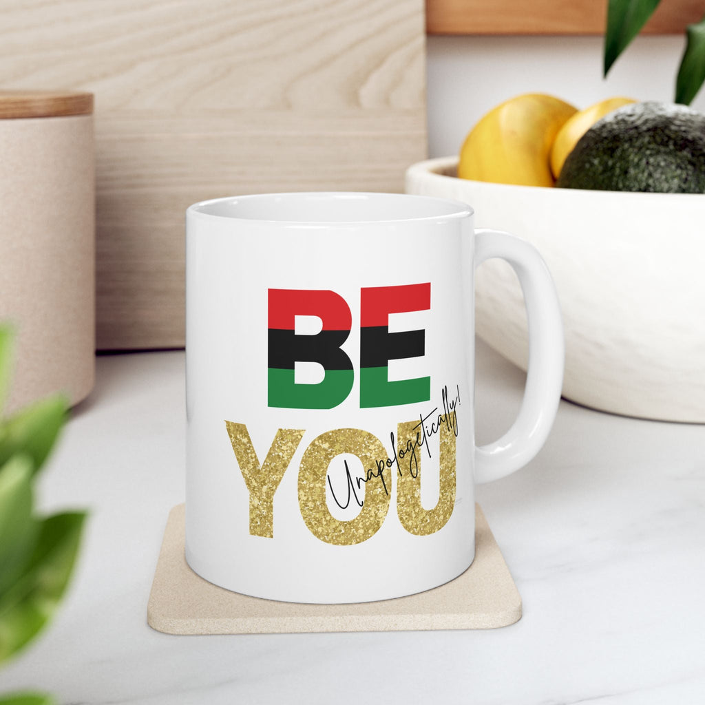 Inspirational Be You White ceramic mug with colorful text on a coaster, surrounded by kitchen items.