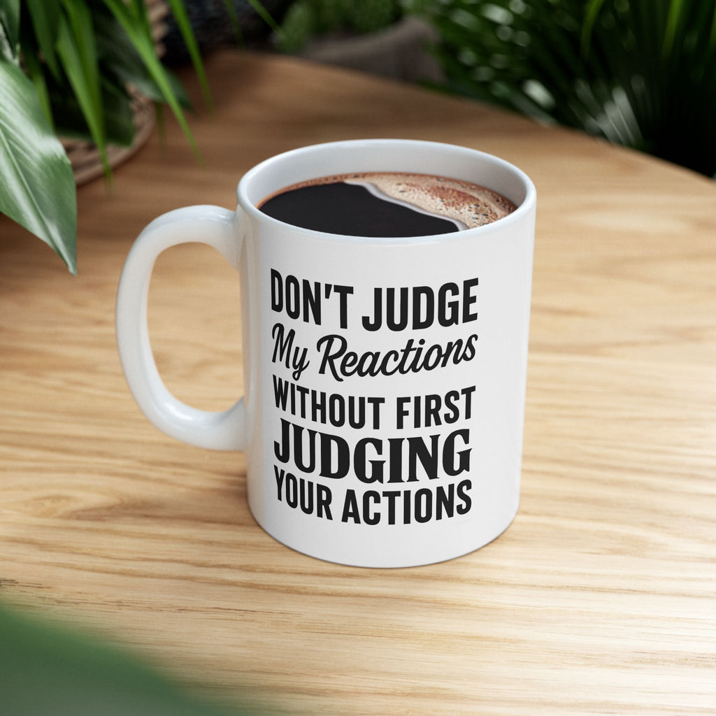 White modern design mug with bold and unapologetic text on a wooden table with coffee