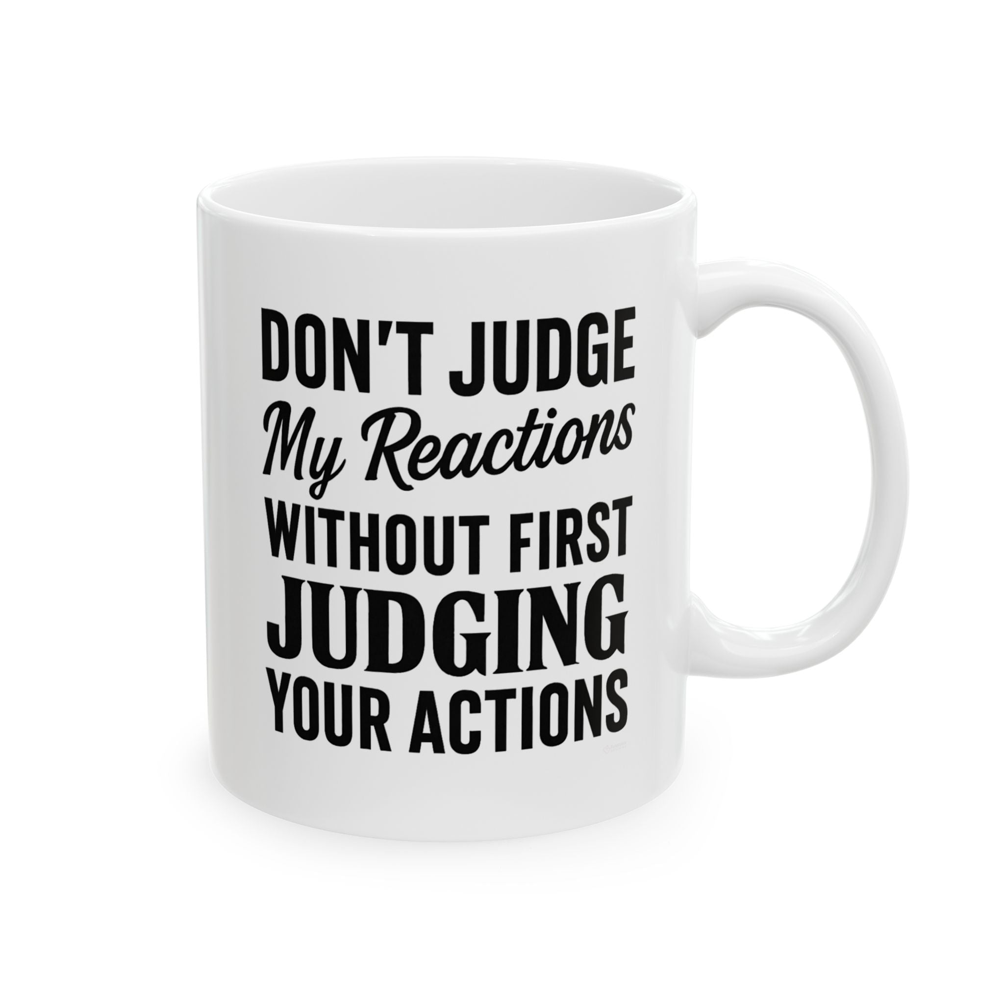 White mug with black text 'DON'T JUDGE MY REACTIONS WITHOUT FIRST JUDGING YOUR ACTIONS' on a white background