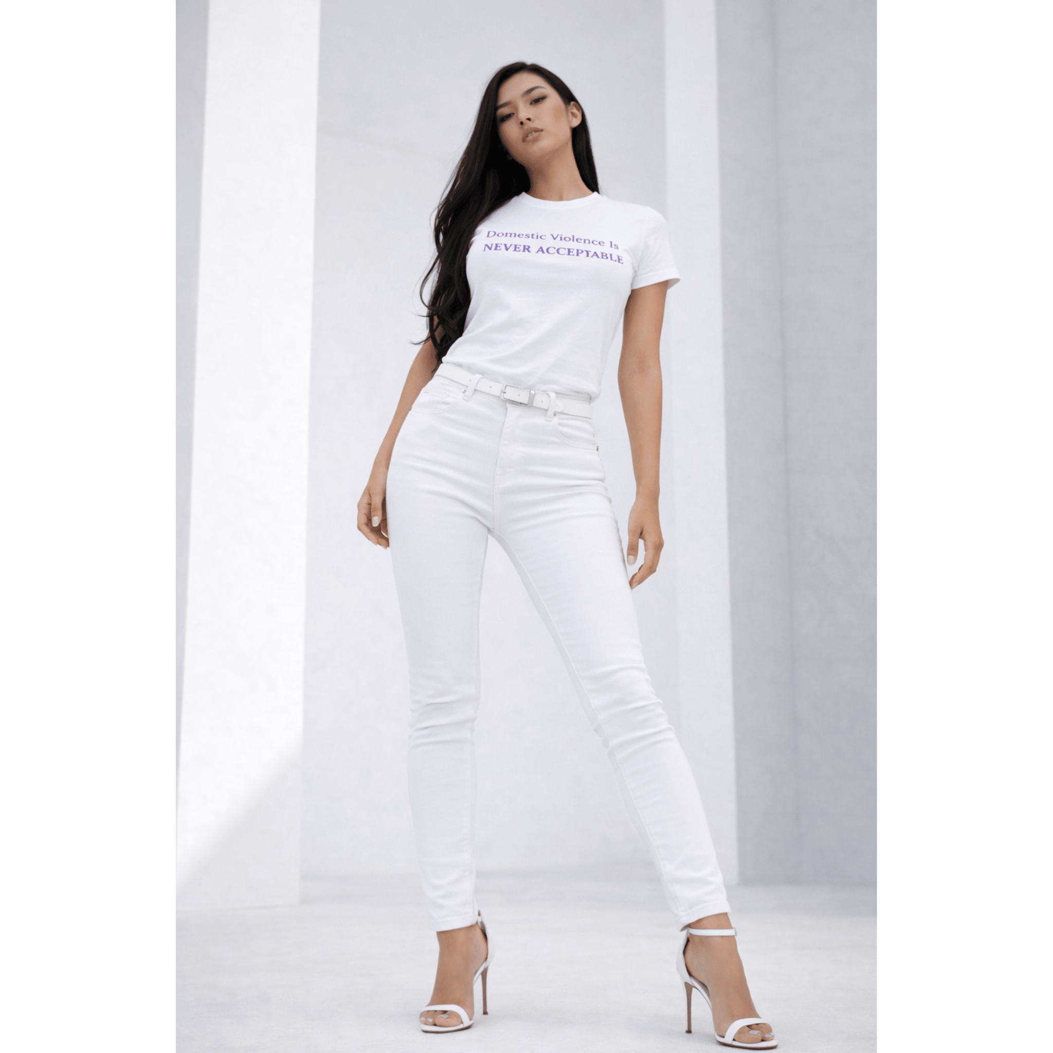 Woman wearing a white t-shirt with text "Domestic Violence Is Never Acceptable" and white pants in a modern pose on a white background by Relatable Designs