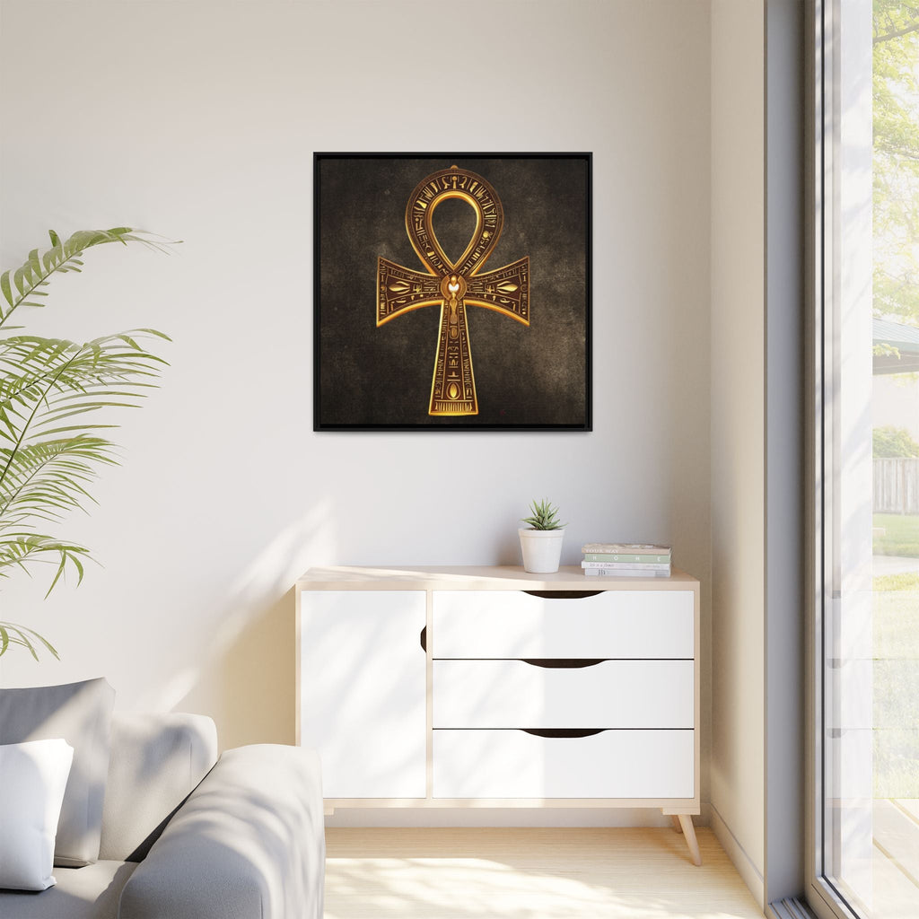 Decorative gold ankh artwork on a wall above a white cabinet with a plant and window in the background.
