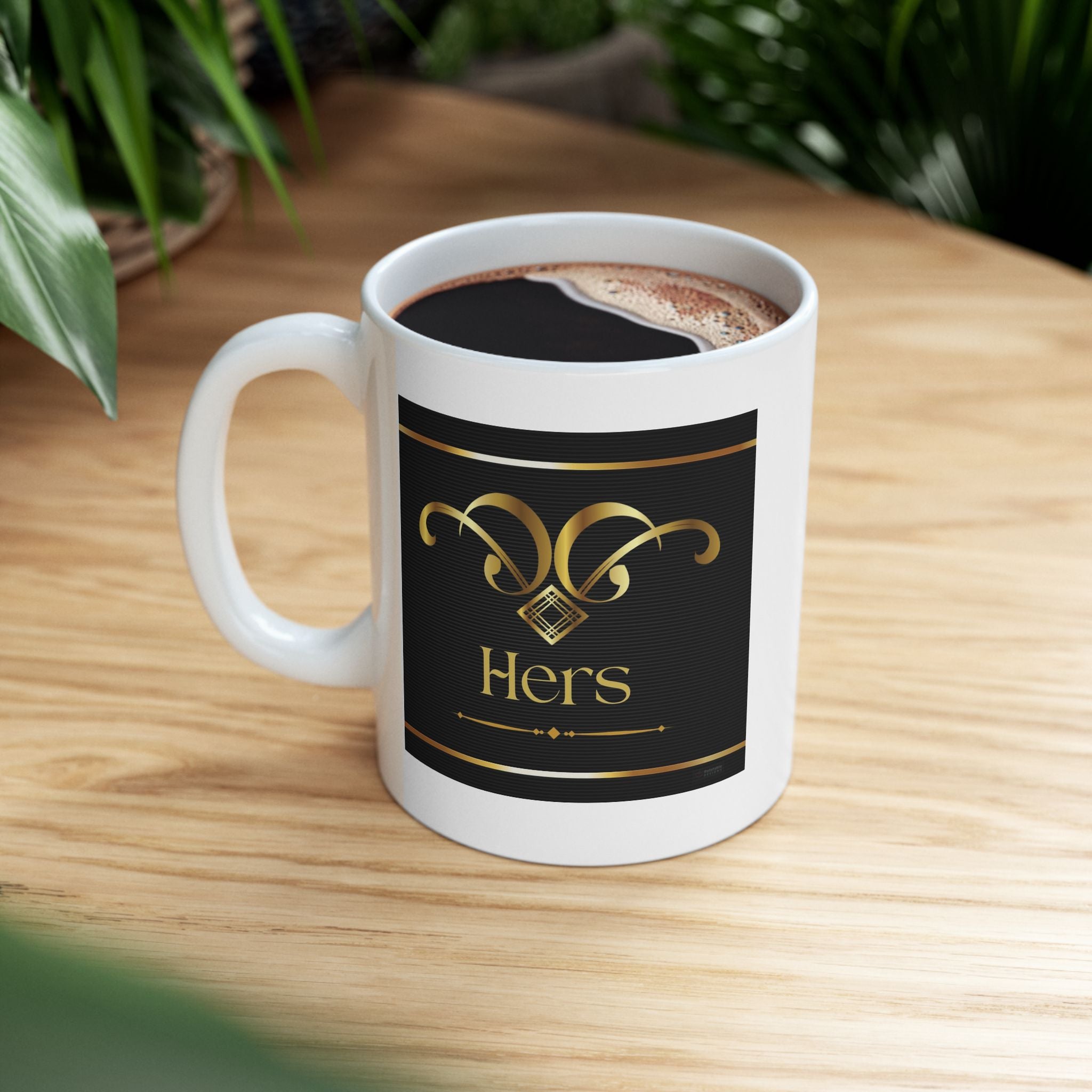 HERS mug with a black label featuring gold text on a wooden surface.