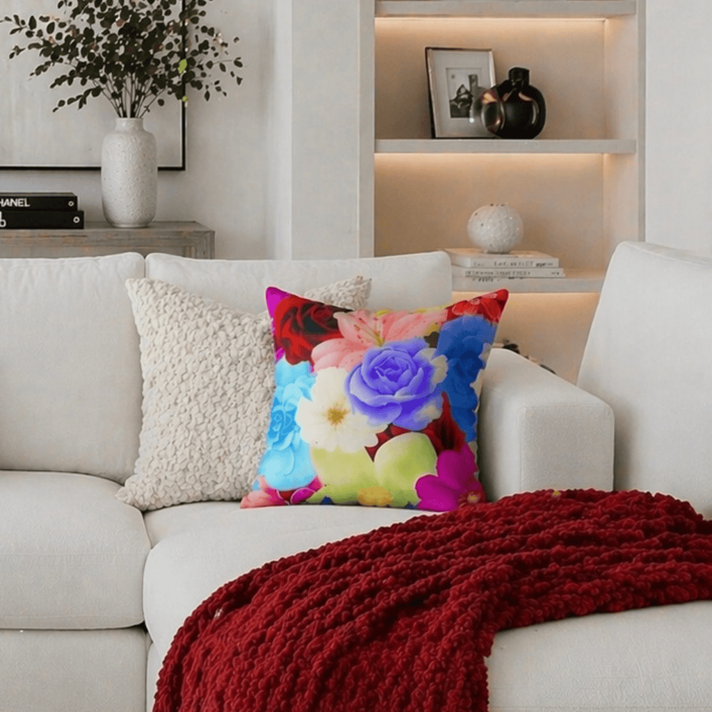 Faux suede decorative pillow with colorful floral design on a white sofa with a red throw blanket.