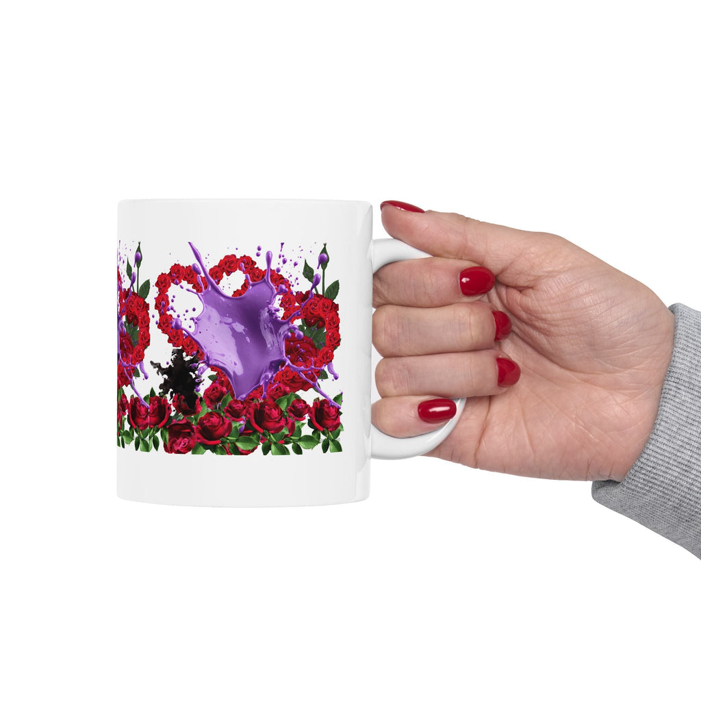 Hand holding a mug with a floral design and purple liquid splash on a white background