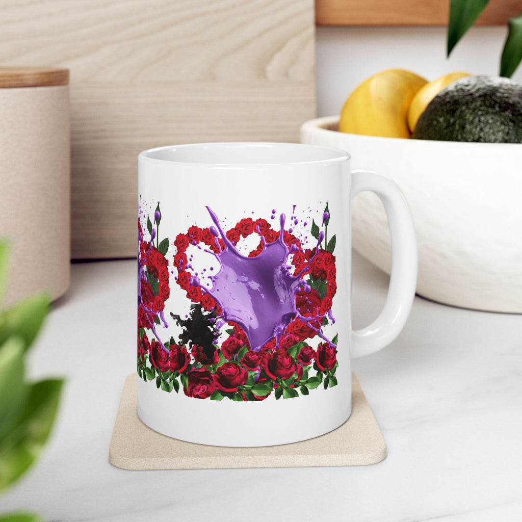 White mug with floral and heart design with purple splash on a coaster, surrounded by kitchen items.