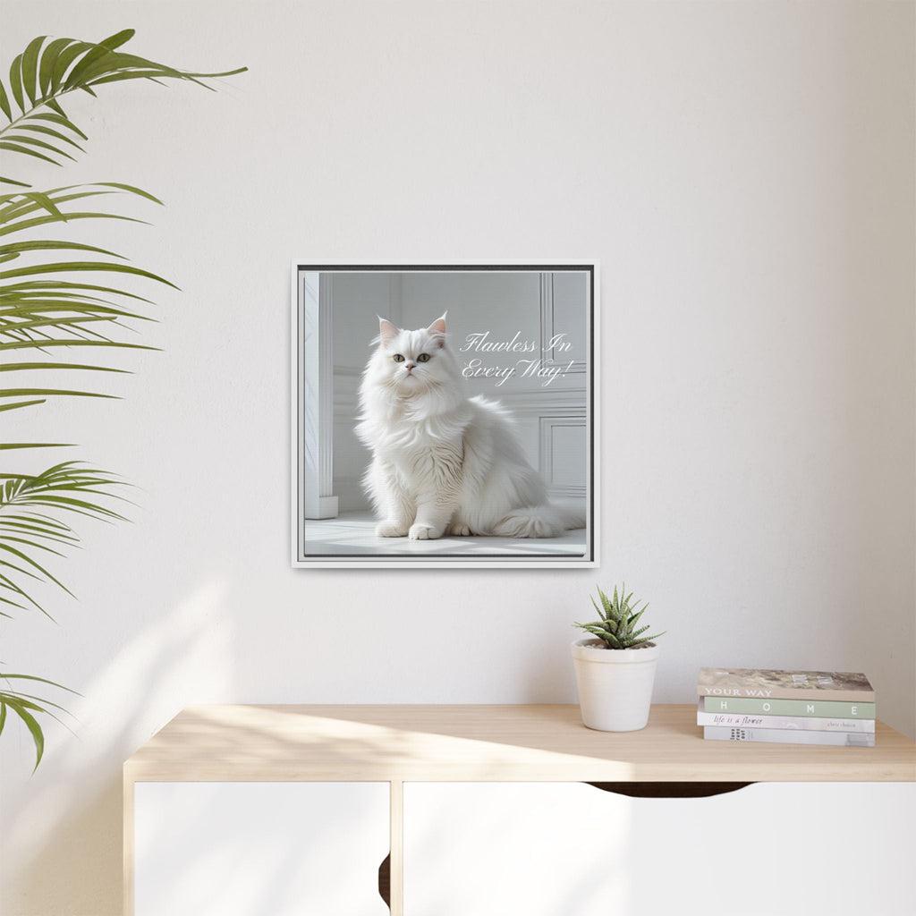 Framed picture of a white cat with text 'Flawless In Every Way' on a wall above a desk with a plant and books.