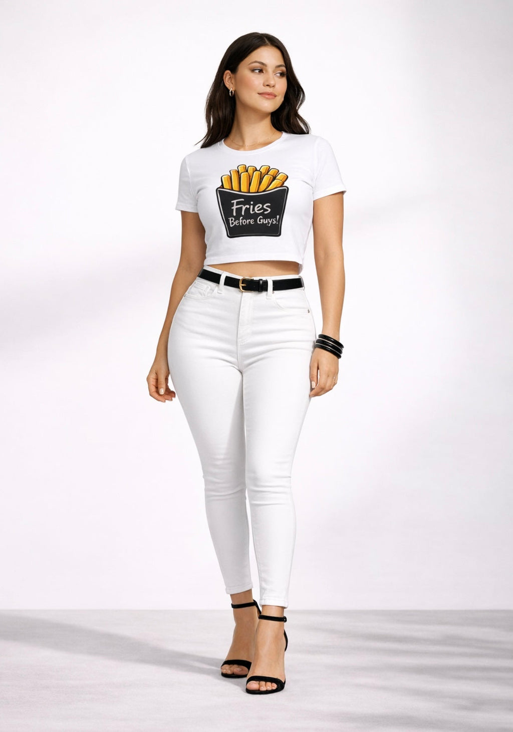 Woman wearing a white t-shirt with a graphic design ‘Fries Before Guys’ and white pants on a white background