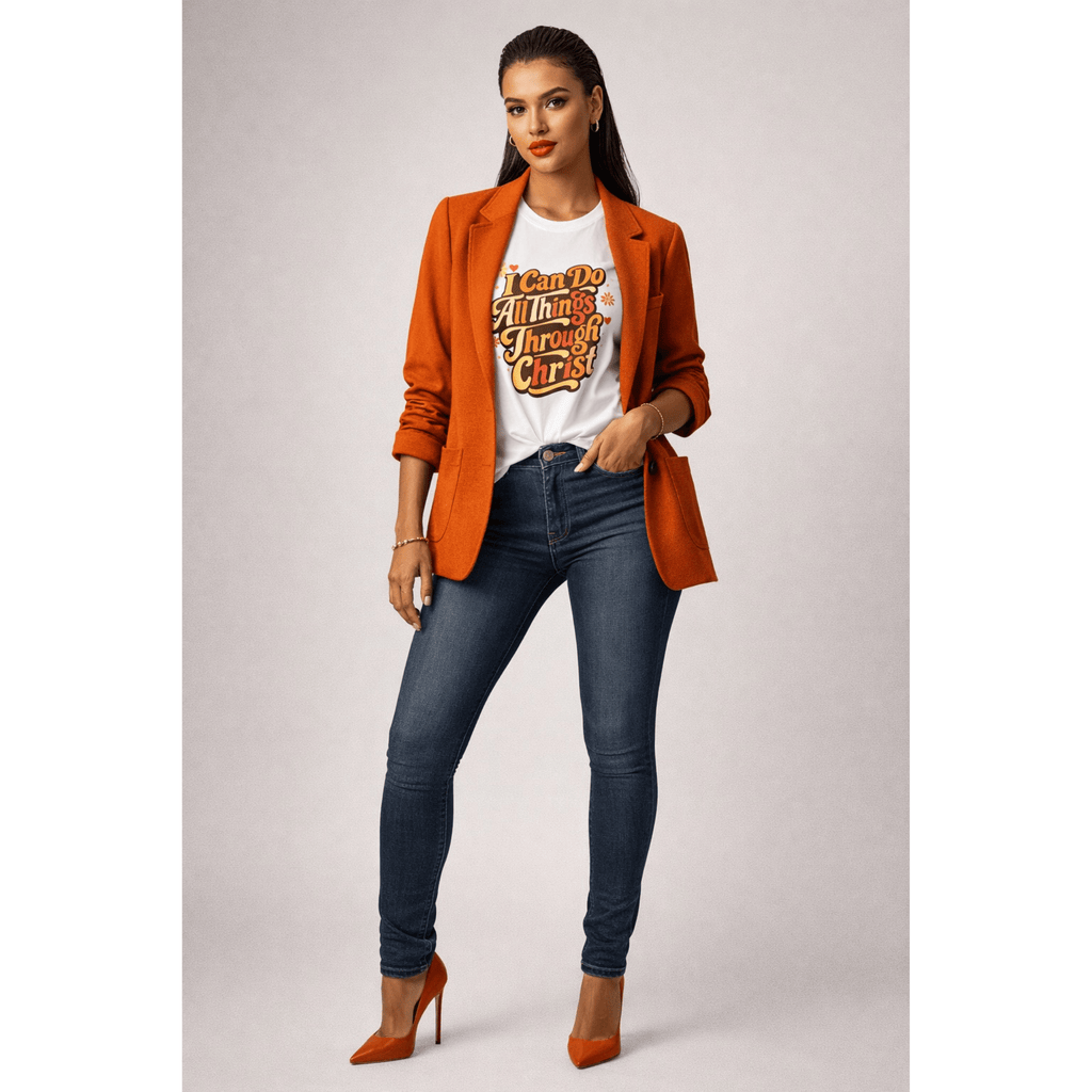 Woman wearing an orange blazer, white t-shirt with inspirational text, and blue jeans on a plain background