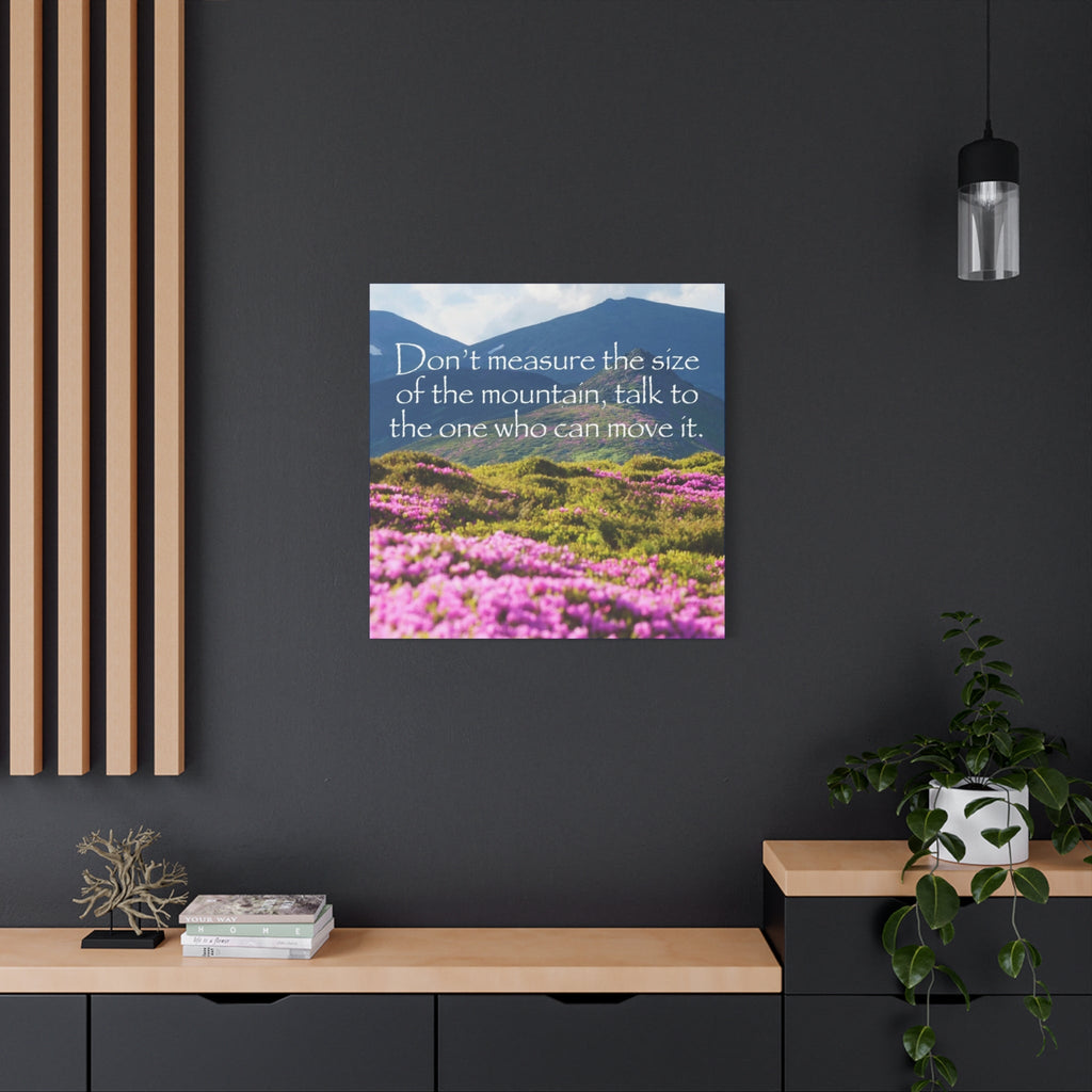 Canvas wall art with mountain and pink flower design with inspirational quote on a dark wall with decor elements.