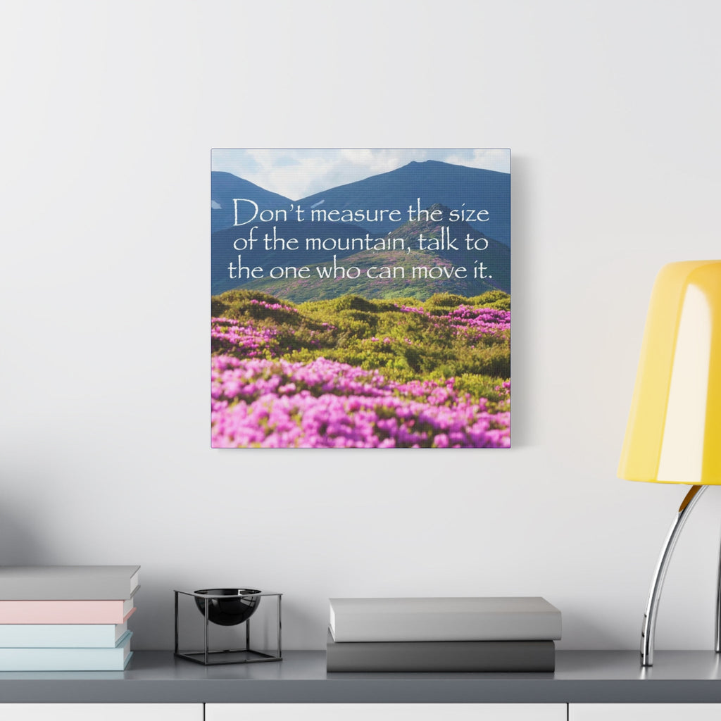 Canvas print with mountain and flower landscape and motivational quote on a wall above a desk.