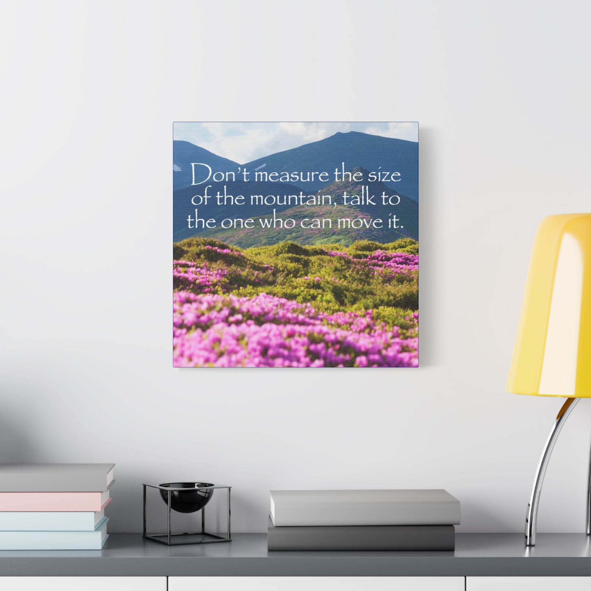 Canvas print with mountain and flower landscape and motivational quote on a wall above a desk.