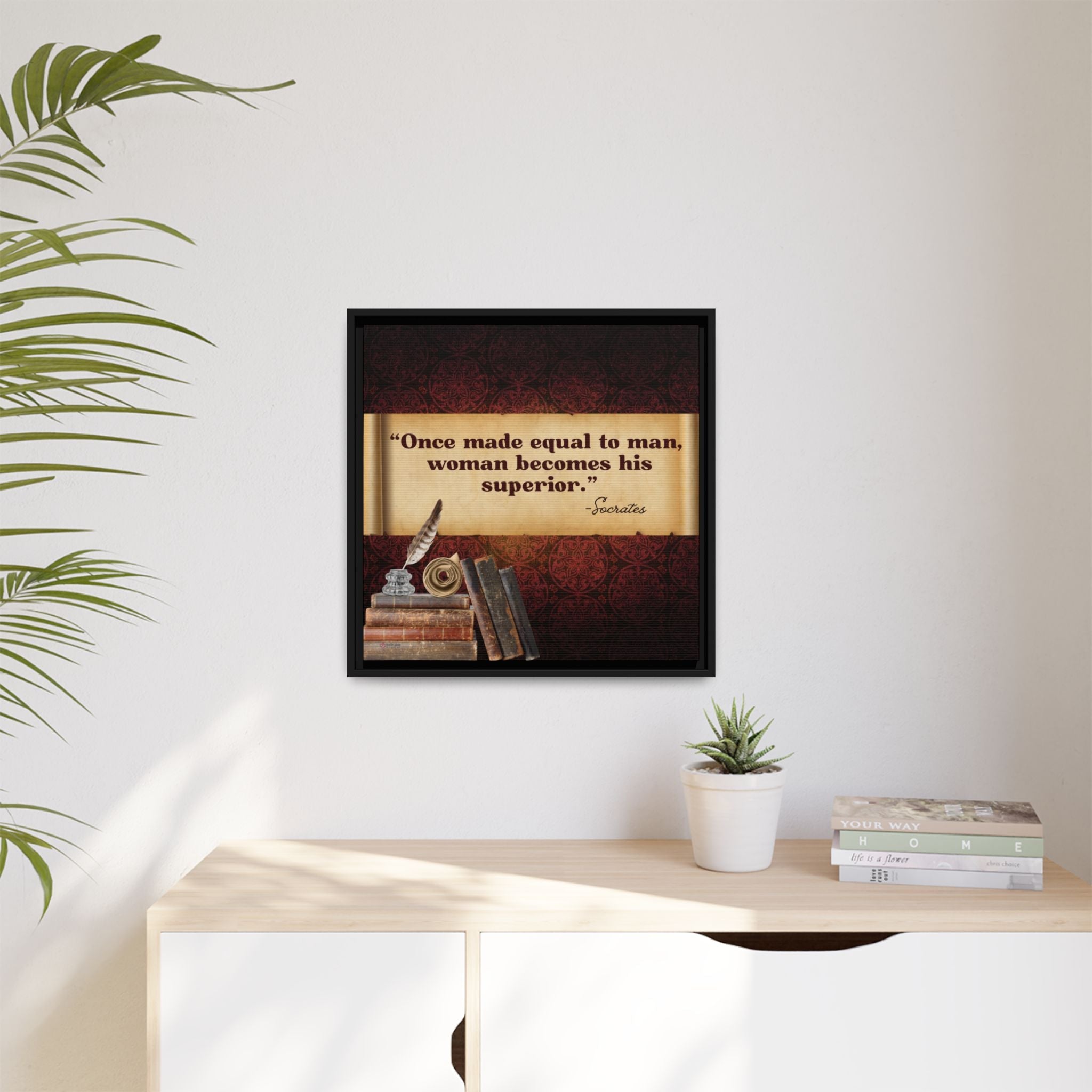 Framed Socrates quote on a wall above a desk with books and a plant.