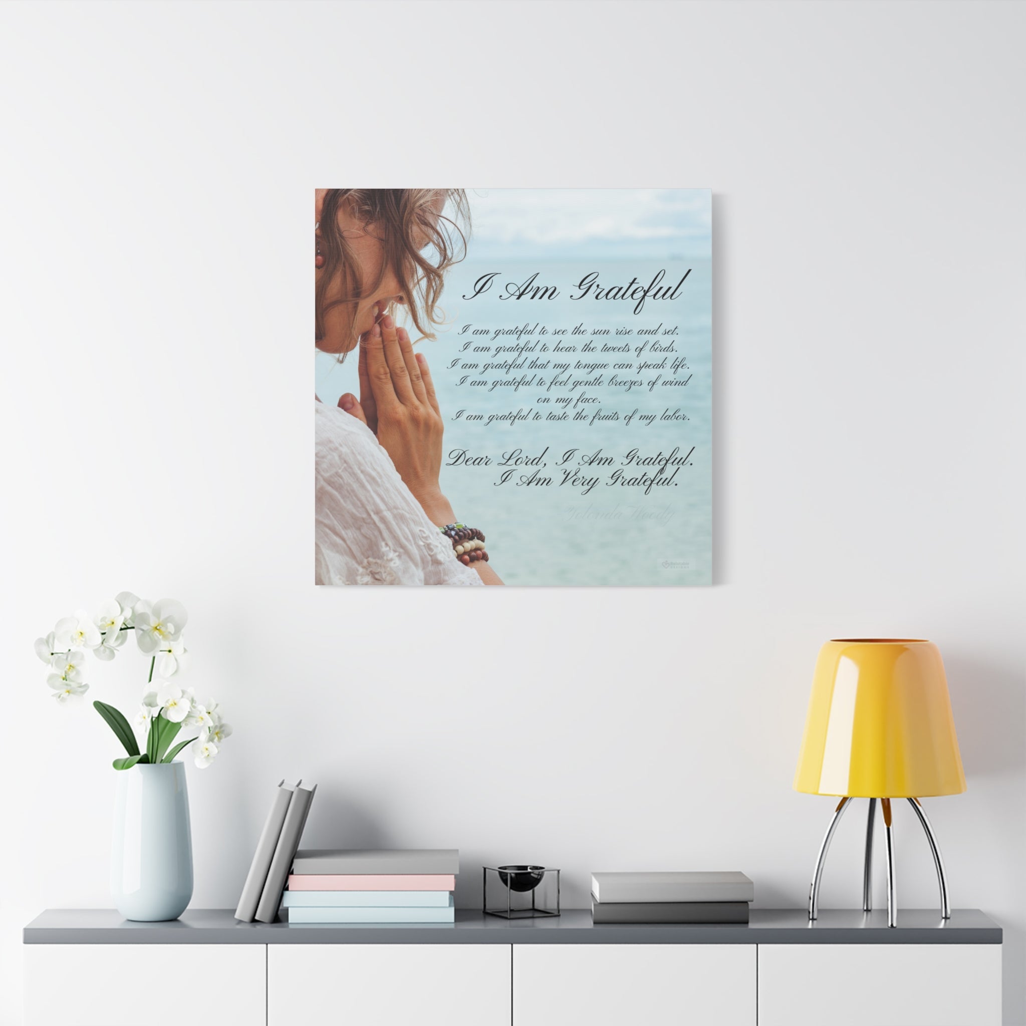 Inspirational Wall art with a woman praying and text on a white wall above a shelf with decor items.