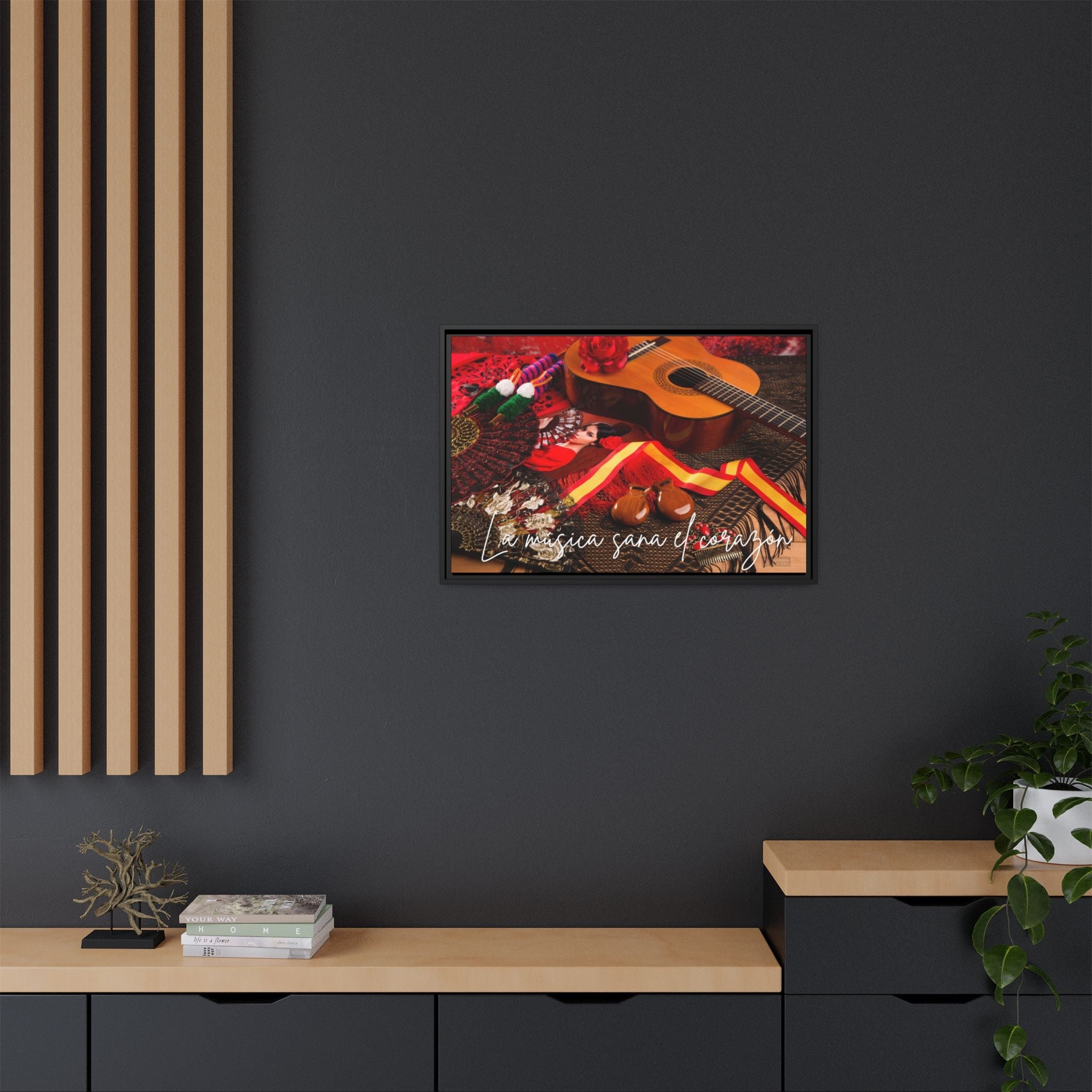 Framed Spanish musical artwork of a guitar and flowers on a dark wall with wooden furniture.