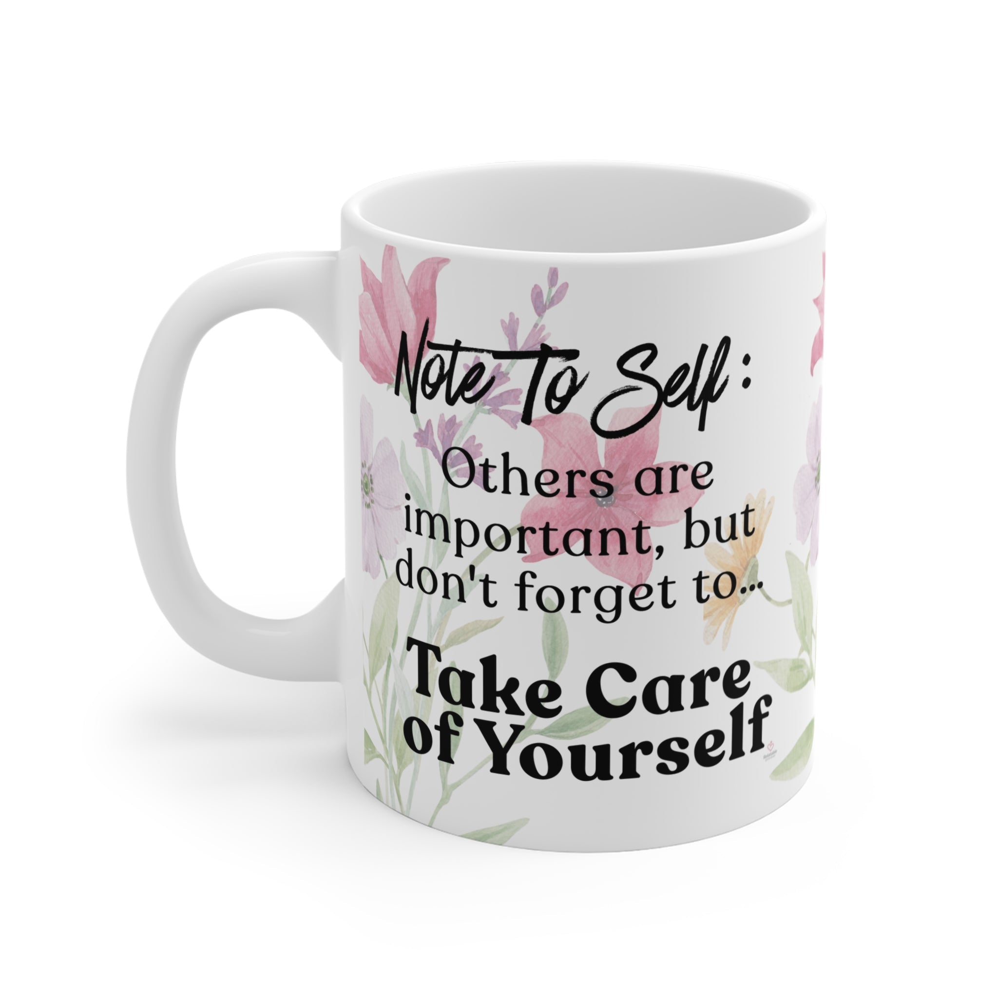 Close-up of “Take Care of Yourself” message on ceramic mug with soft pastel floral accents