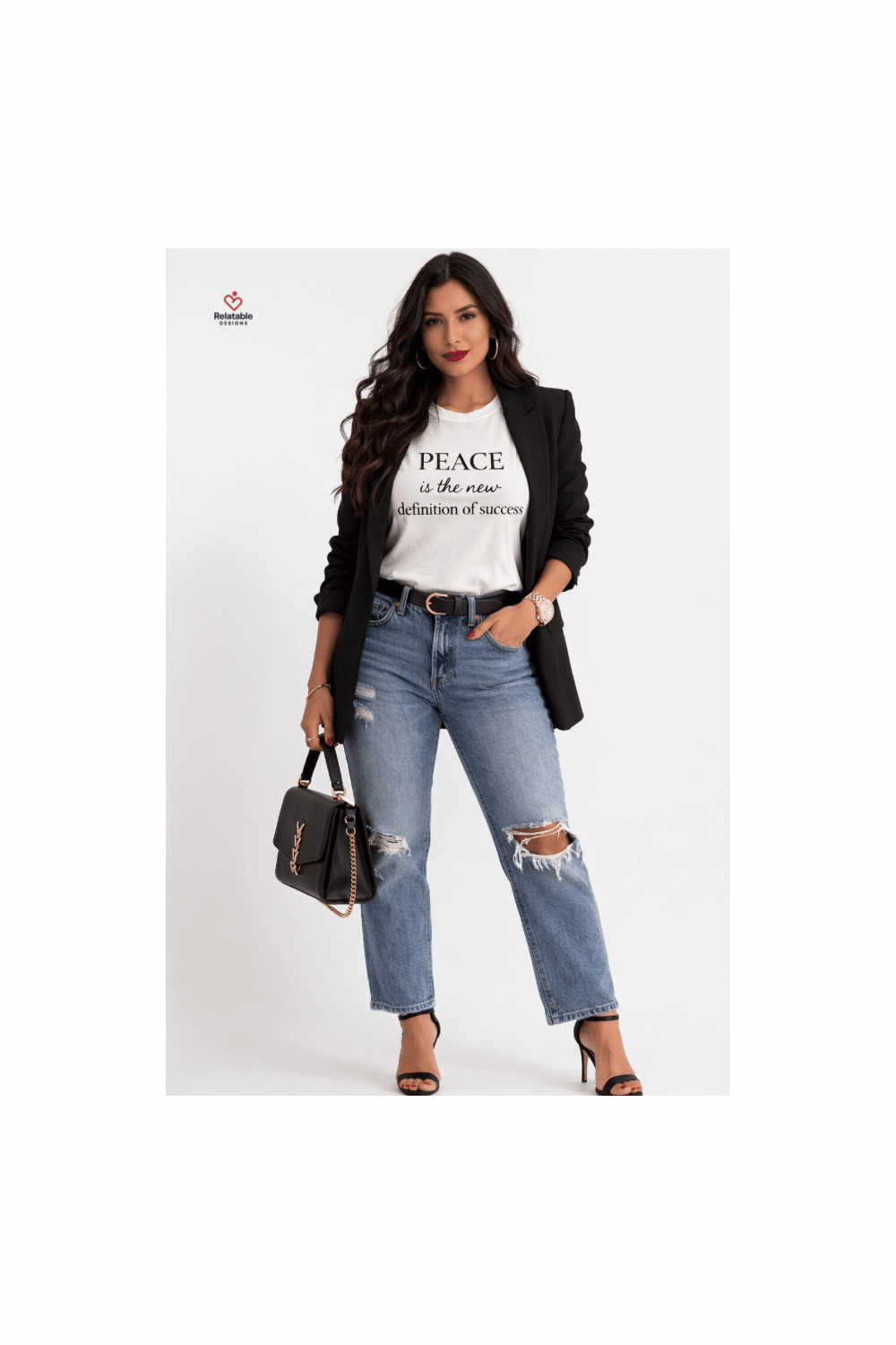 Woman wearing a white t-shirt with inspirational text, black blazer, and ripped jeans on a white background