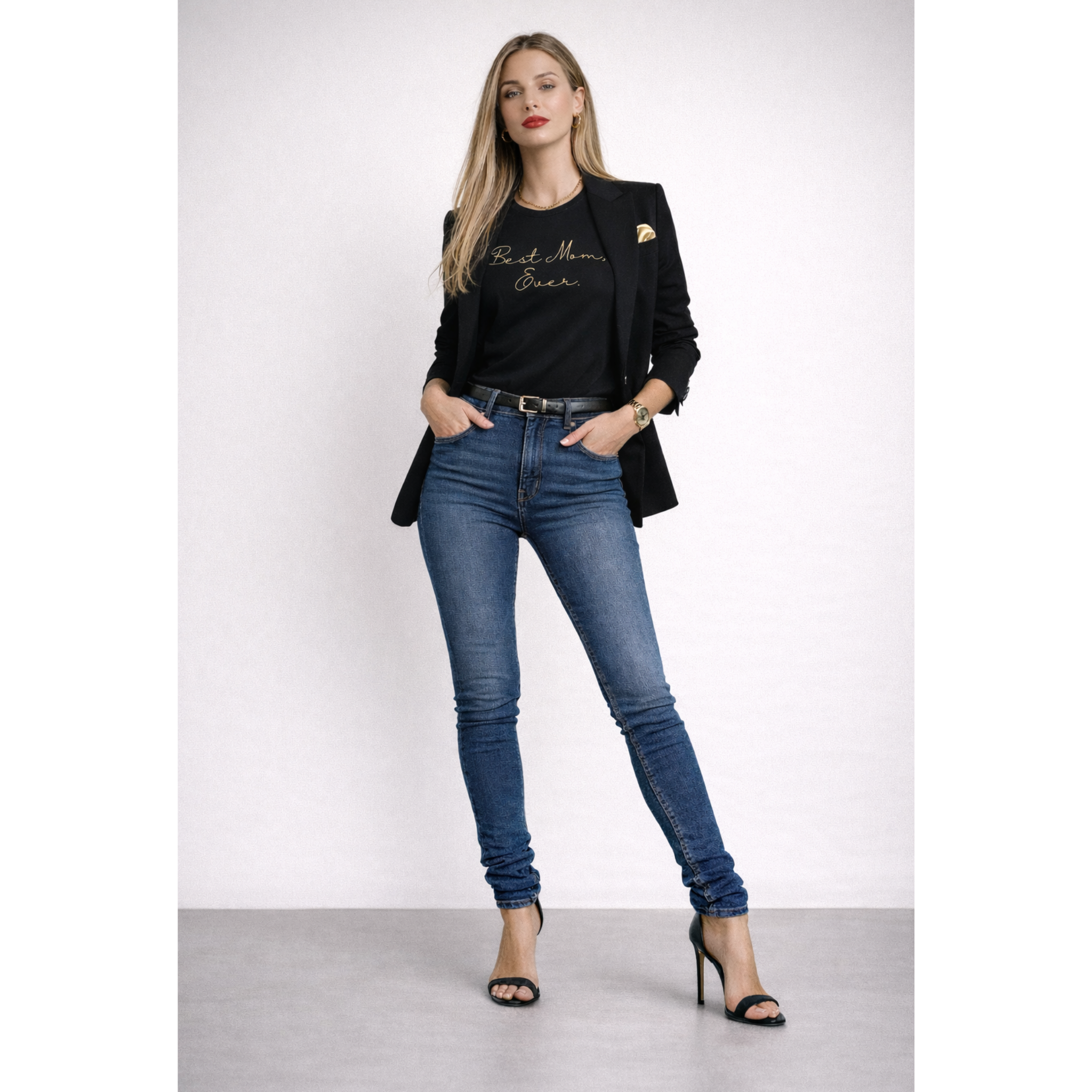Woman wearing a black blazer with text, blue jeans, and high heels on a white background