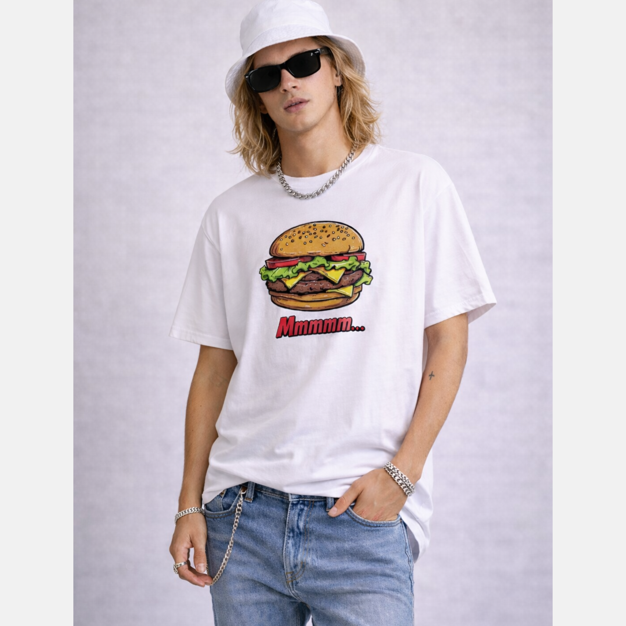 Man wearing sunglasses and white fisher hat with a white t-shirt with a burger graphic and 'Mmmmm' text, standing against a plain background.