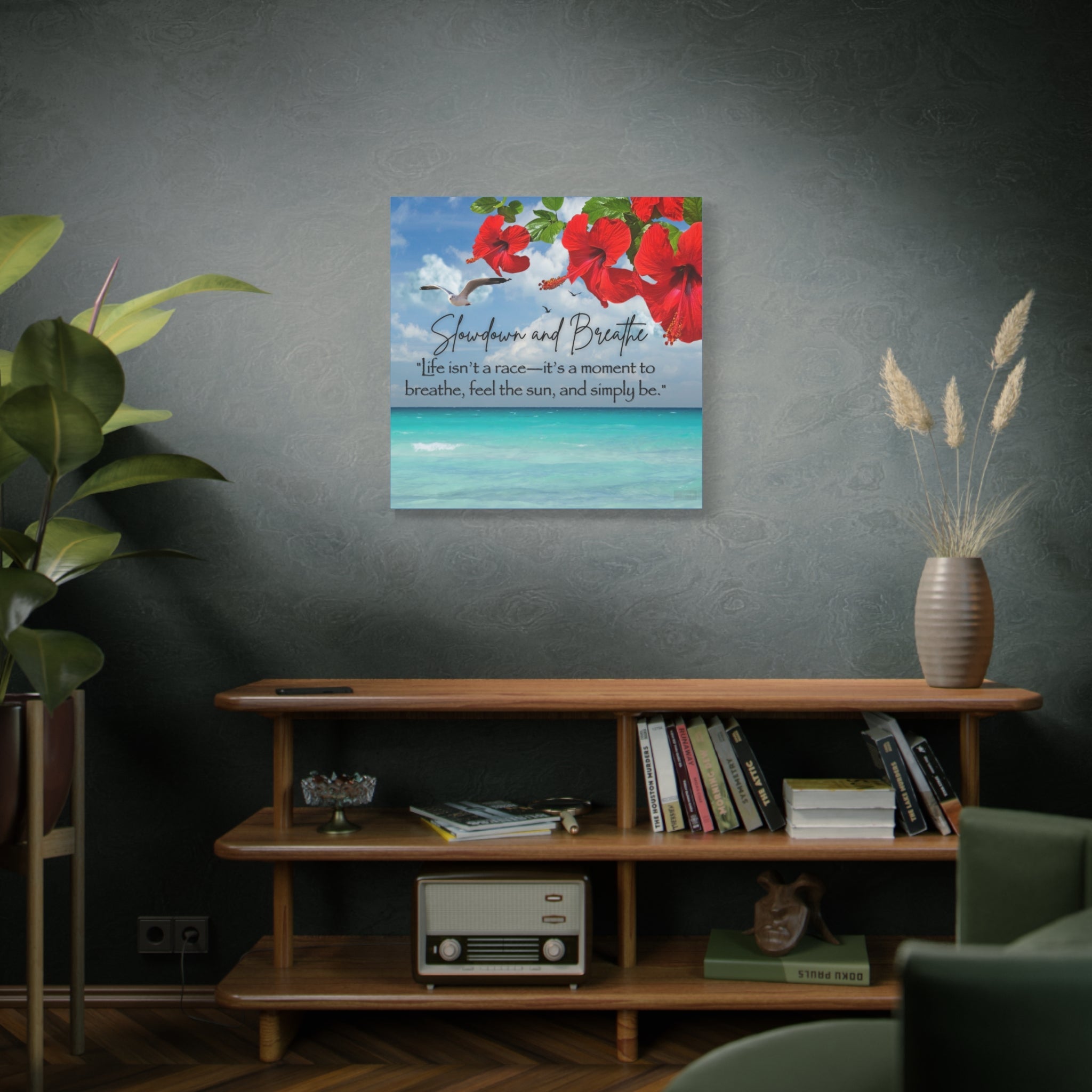 Decorative wall art with tropical red flowers and text on a gray wall above a wooden shelf.