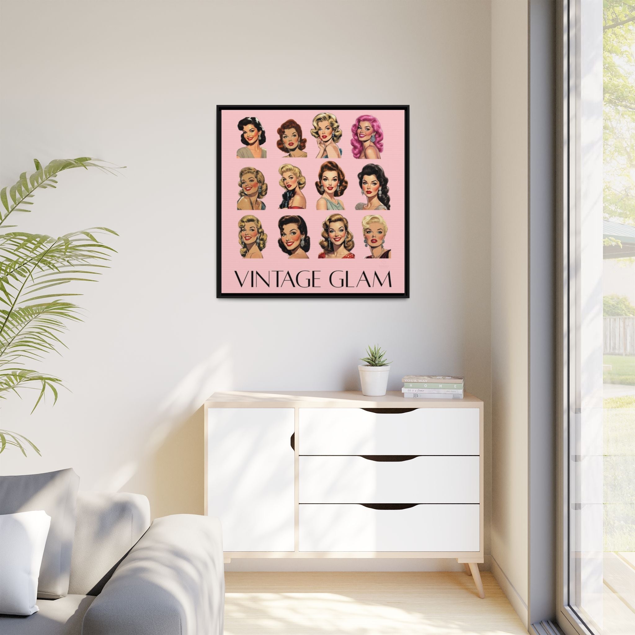 Framed 'Vintage Glam' canvas artwork on a wall above a white cabinet with a plant and window in the background.