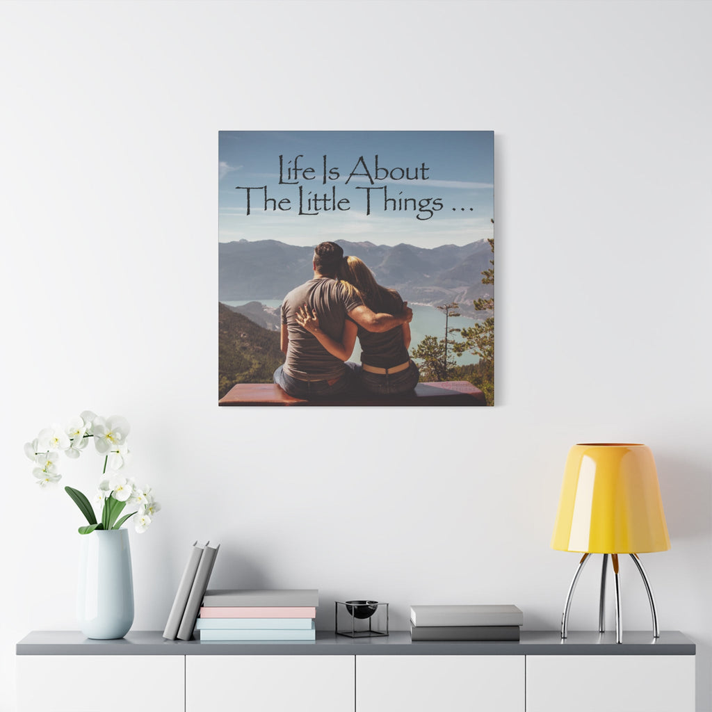 Canvas print with a couple sitting together and 'Life is About The Little Things' text, displayed on a wall above a shelf.