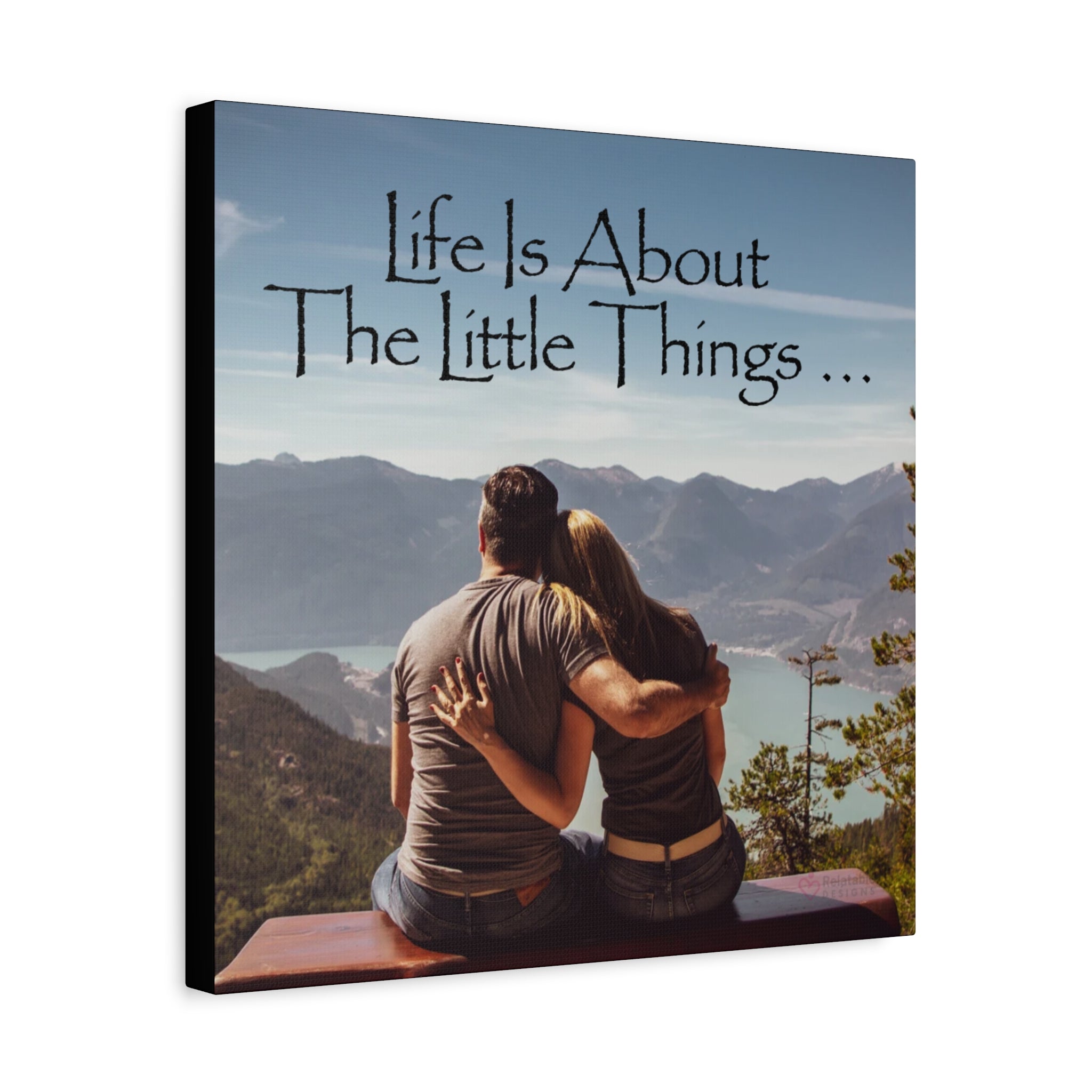 Canvas wall art with a couple sitting on a mountain, overlooking a lake, with text 'Life Is About The Little Things'.