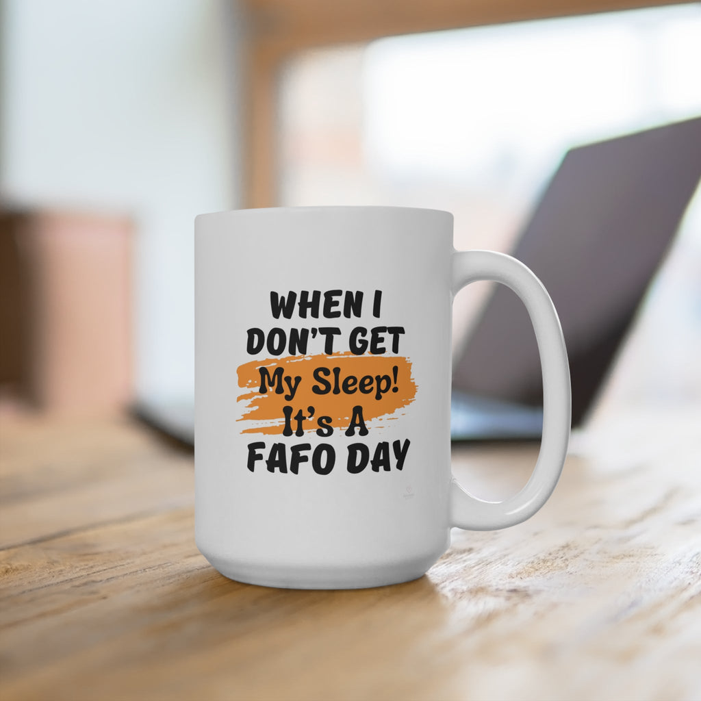 Funny morning white mug with quote about sleep and attitude sitting on wooden desk and laptop in background.