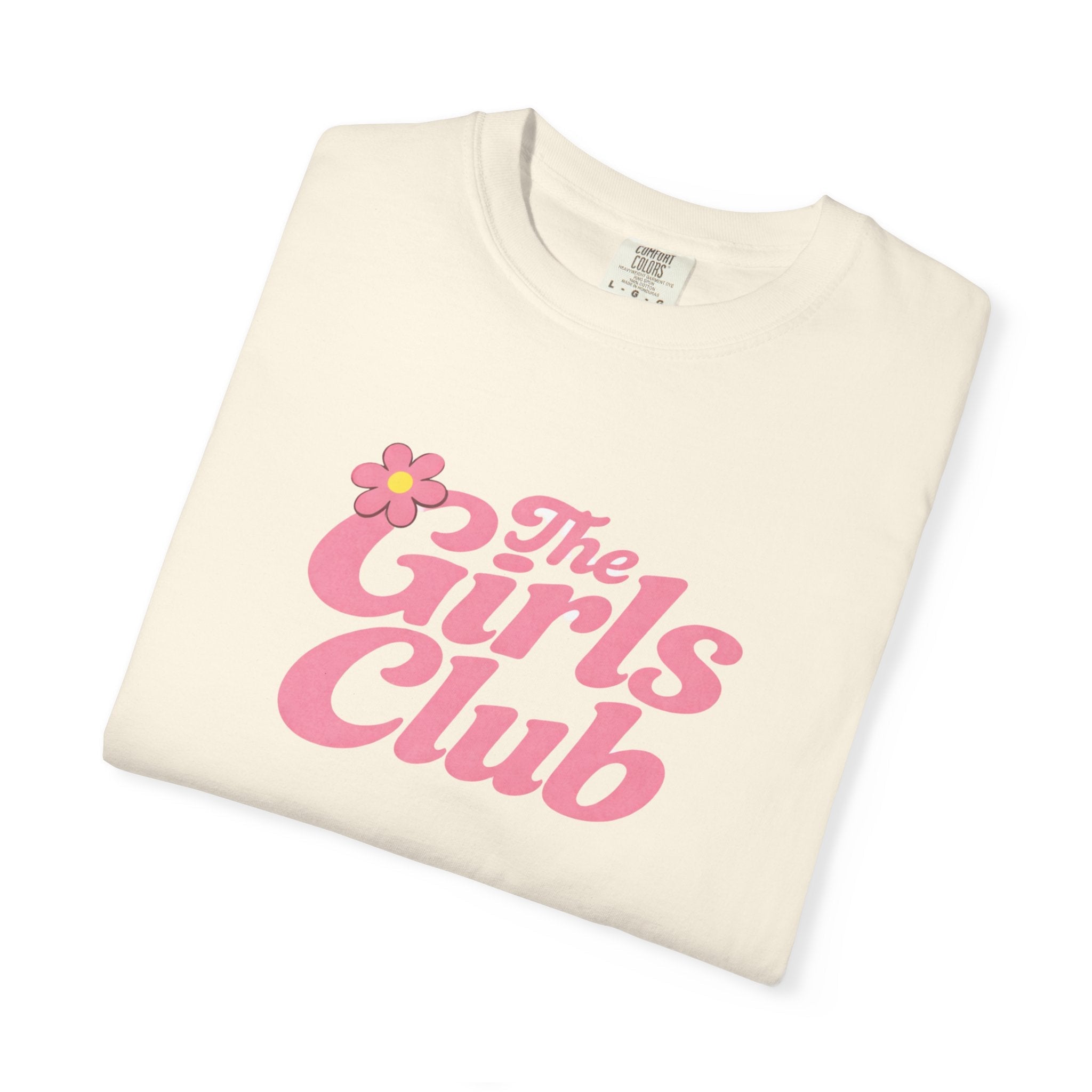 Folded cream t-shirt with 'The Girls Club' text and flower graphic on a white background
