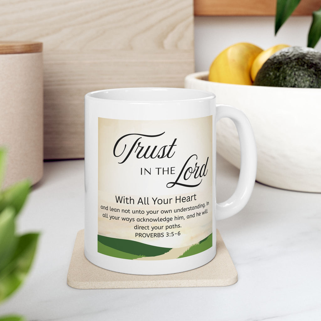 White mug with motivational quote on a coaster, placed on a surface with a plant and container in the background.