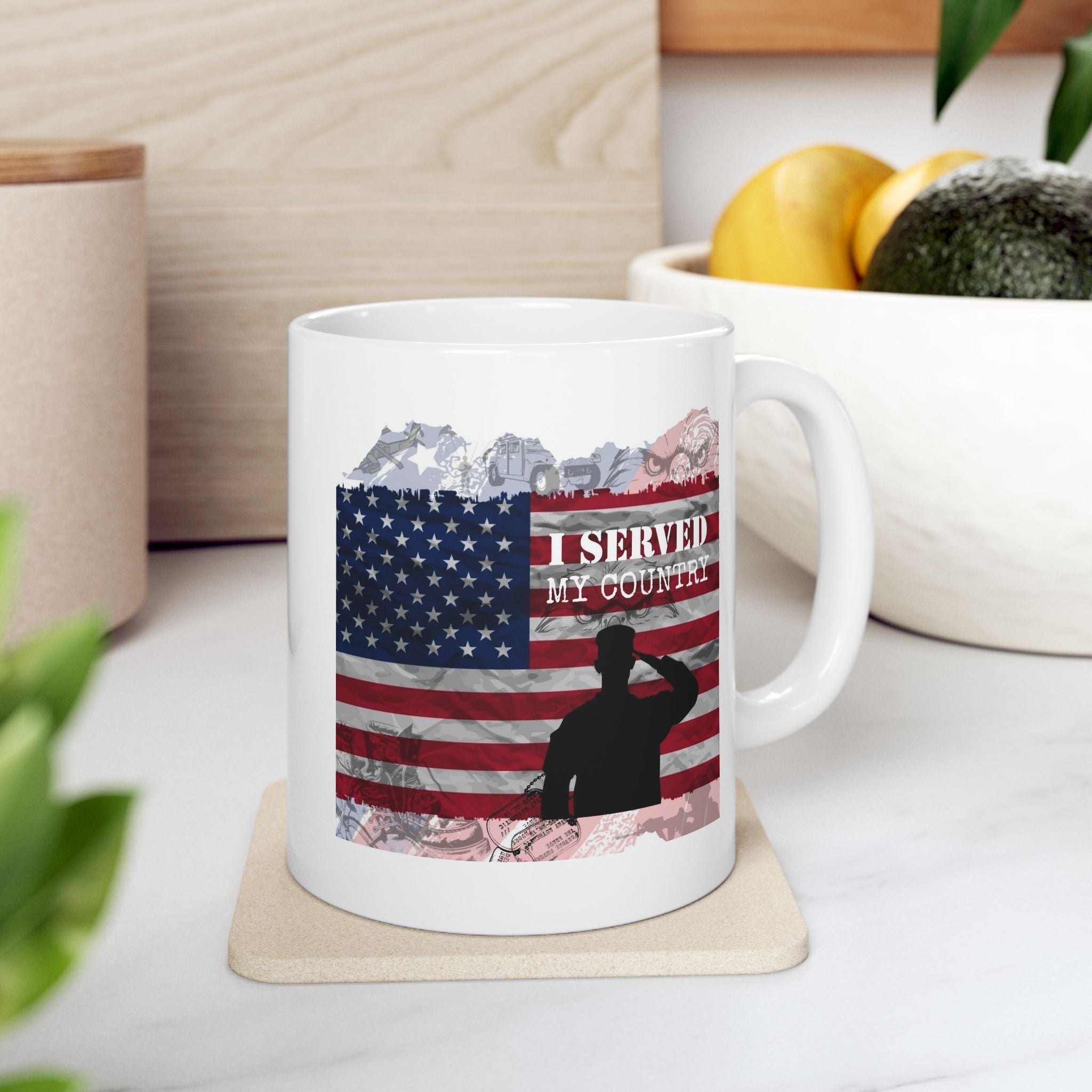 White ceramic mug with American flag design and silhouette of a soldier saluting, placed on a coaster.